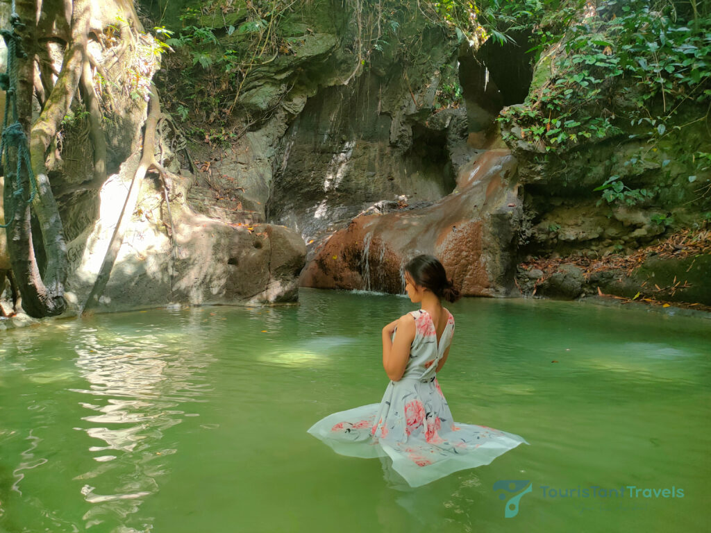 A woman in a floral dress in the water of Busay falls.