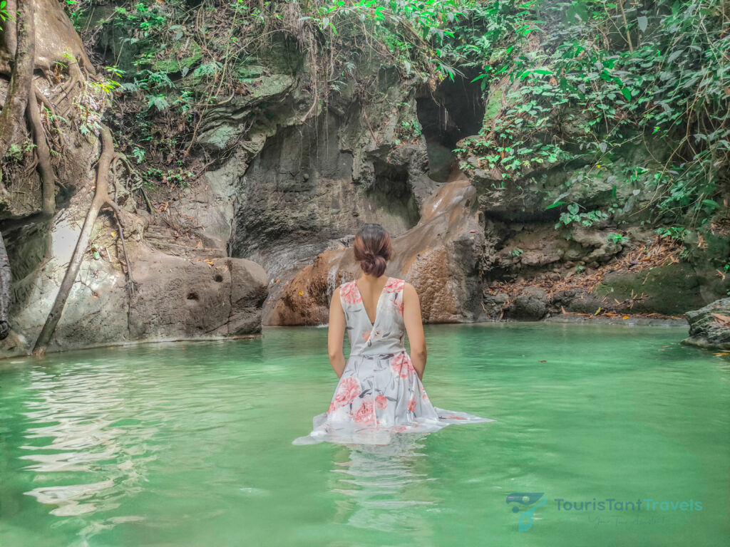 A woman in a floral dress in the water of Busay falls.