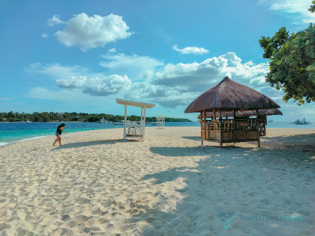 A beach view with a cottage and a person.
